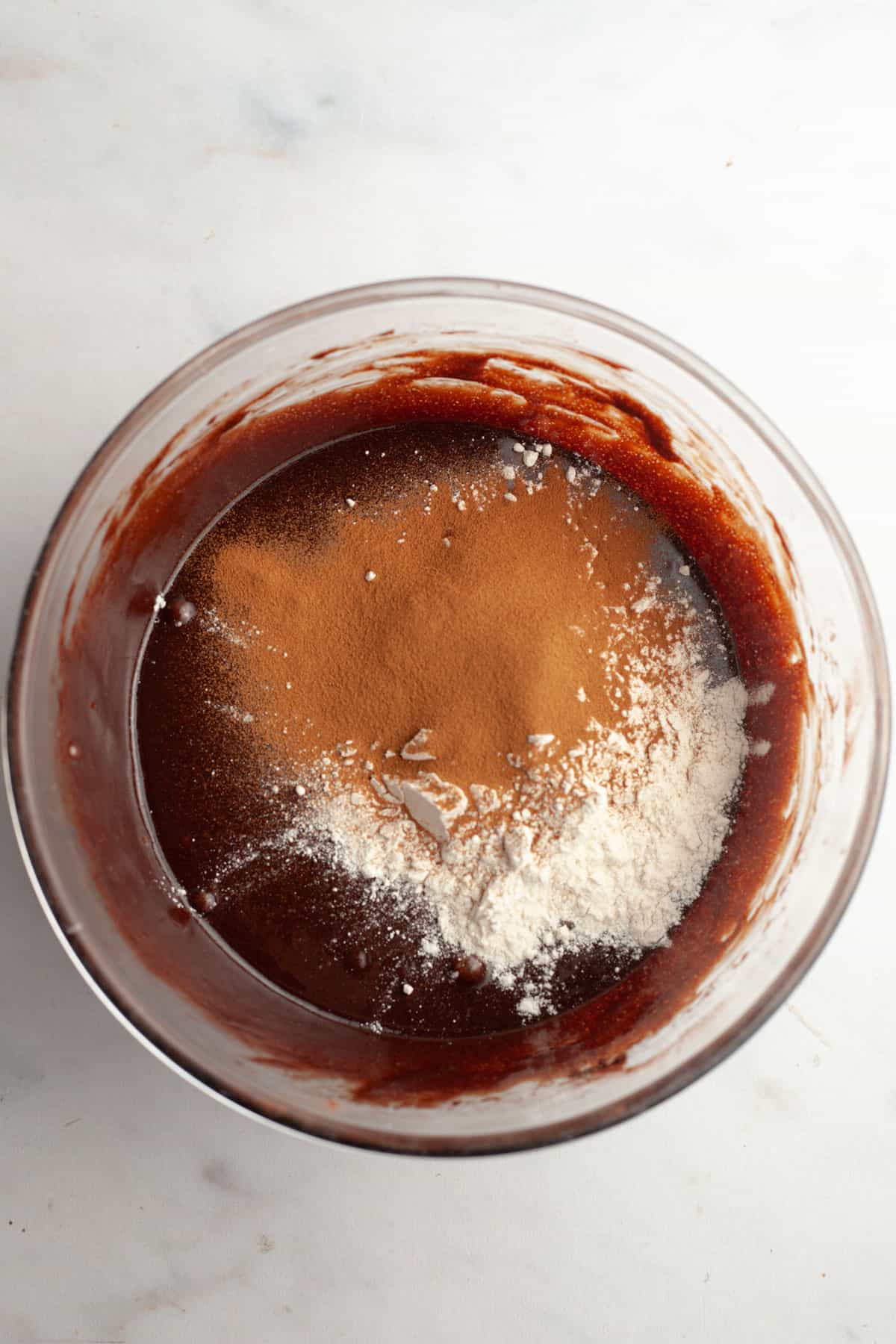 A bowl with brownie batter, flour, and espresso powder in it.