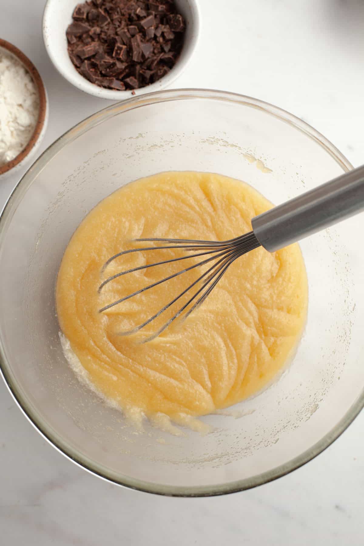 A glass bowl with sugar and melted butter.