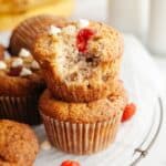 Two raspberry banana muffins stacked on top of each other, one has a bite taken out of it.