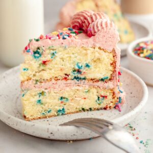 A slice of strawberry funfetti cake on a small plate.