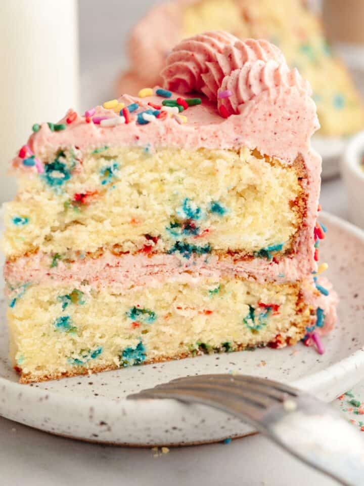 A slice of strawberry funfetti cake on a small plate.