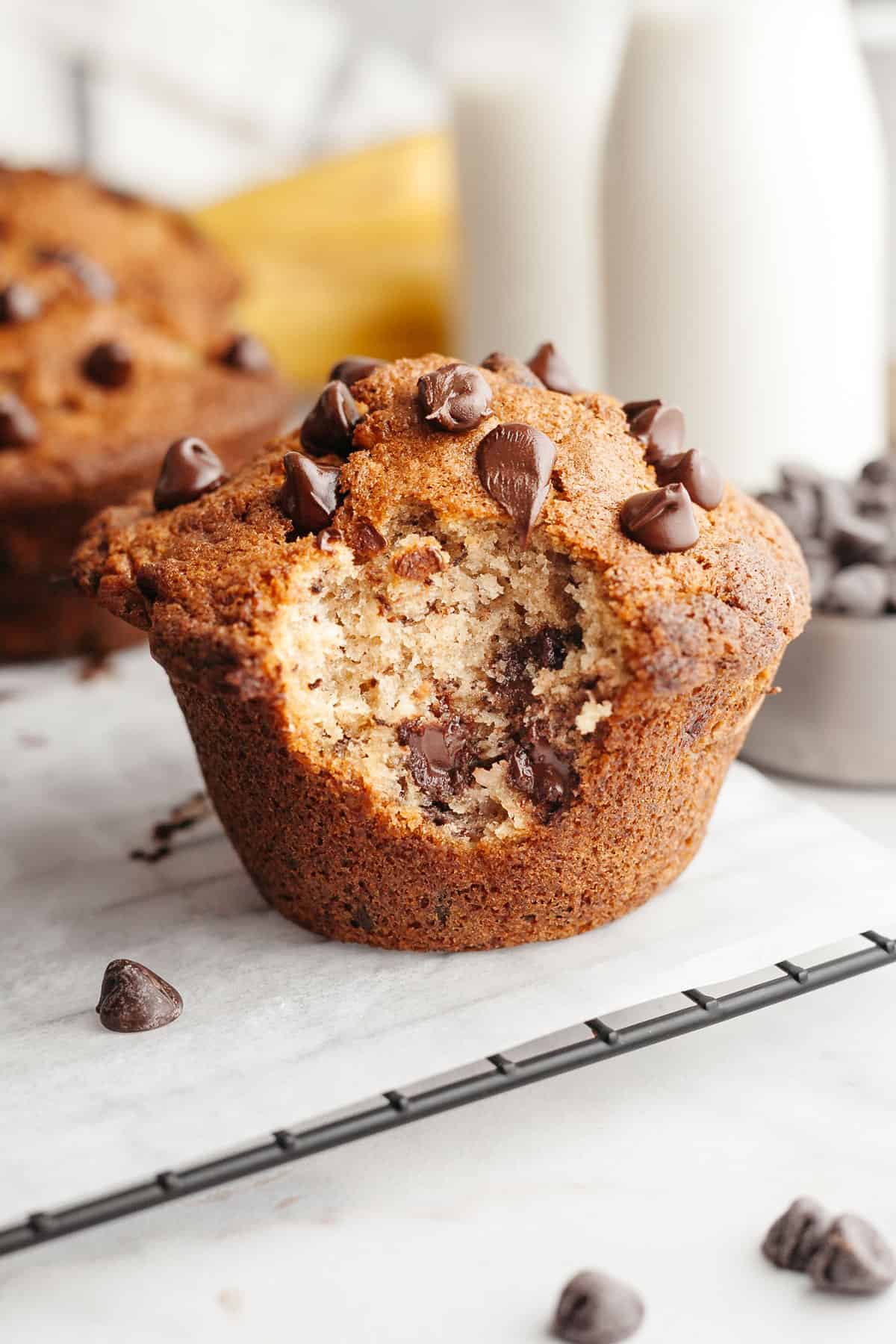 A close up of a jumbo banana chocolate chip muffin with a bite taken out of it.