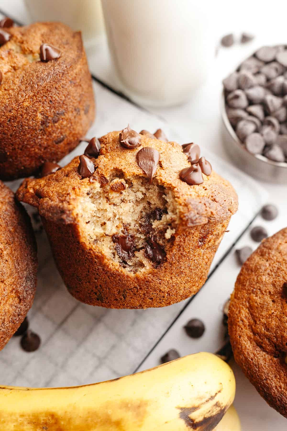 A close up of a jumbo banana chocolate chip muffin with a bite taken out of it.