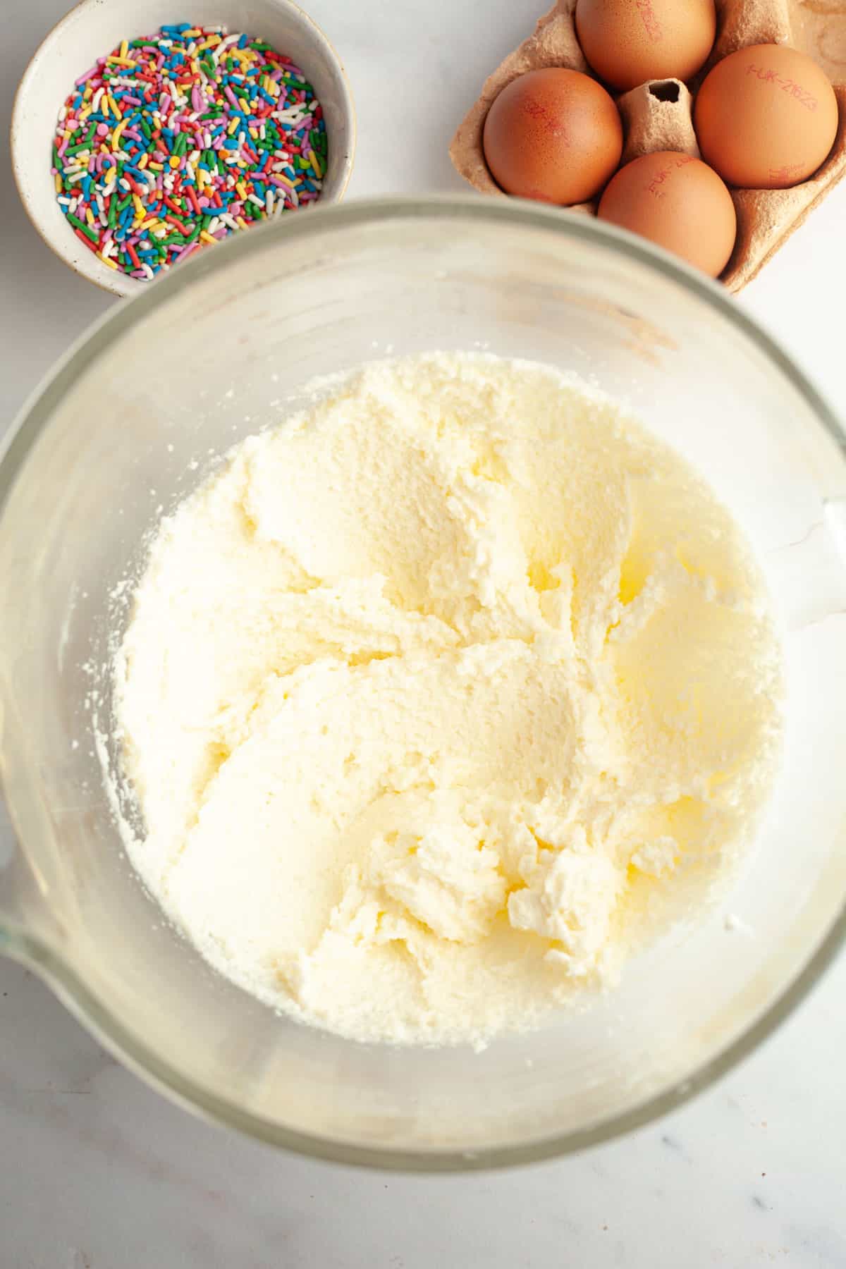 Whipped butter and sugar in a glass mixing bowl.