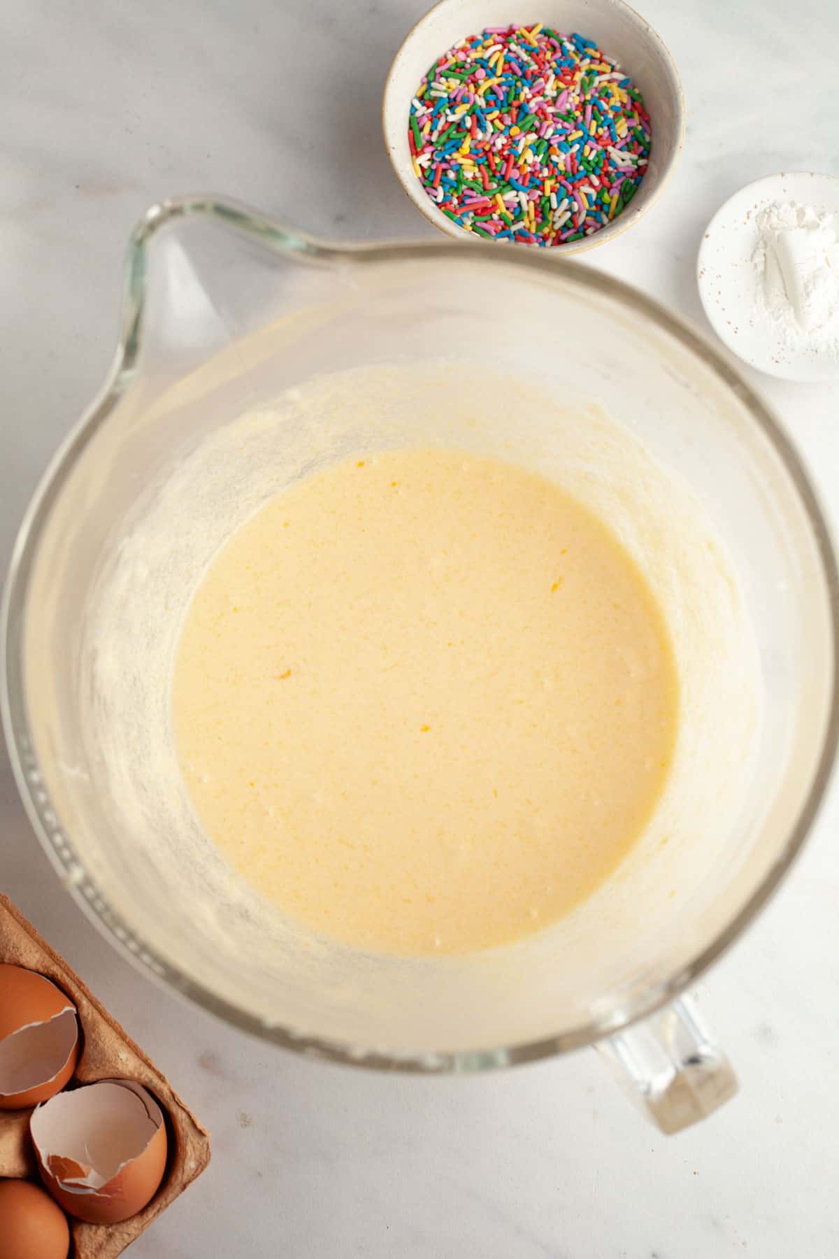 A large glass mixing bowl with cake batter in it.