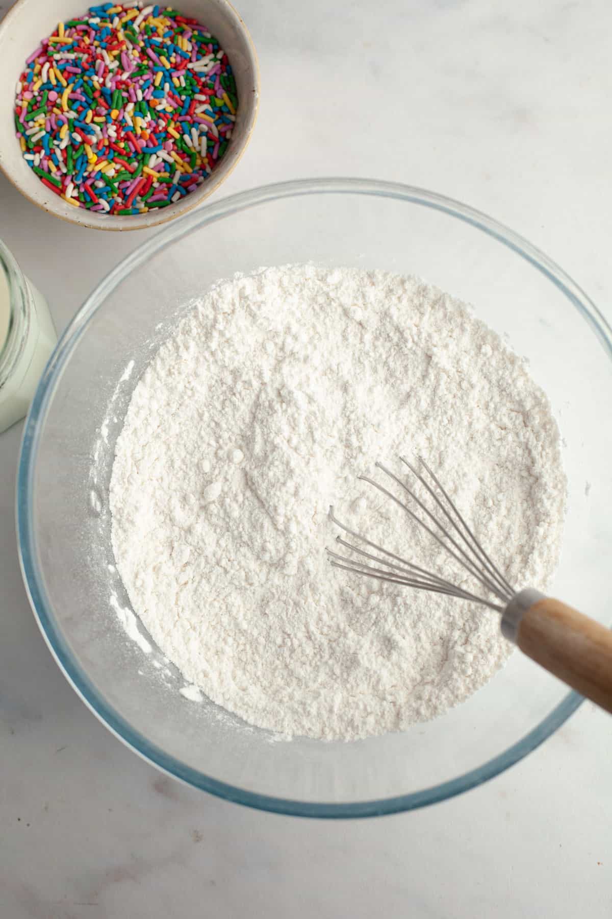 A bowl with flour and a whisk.