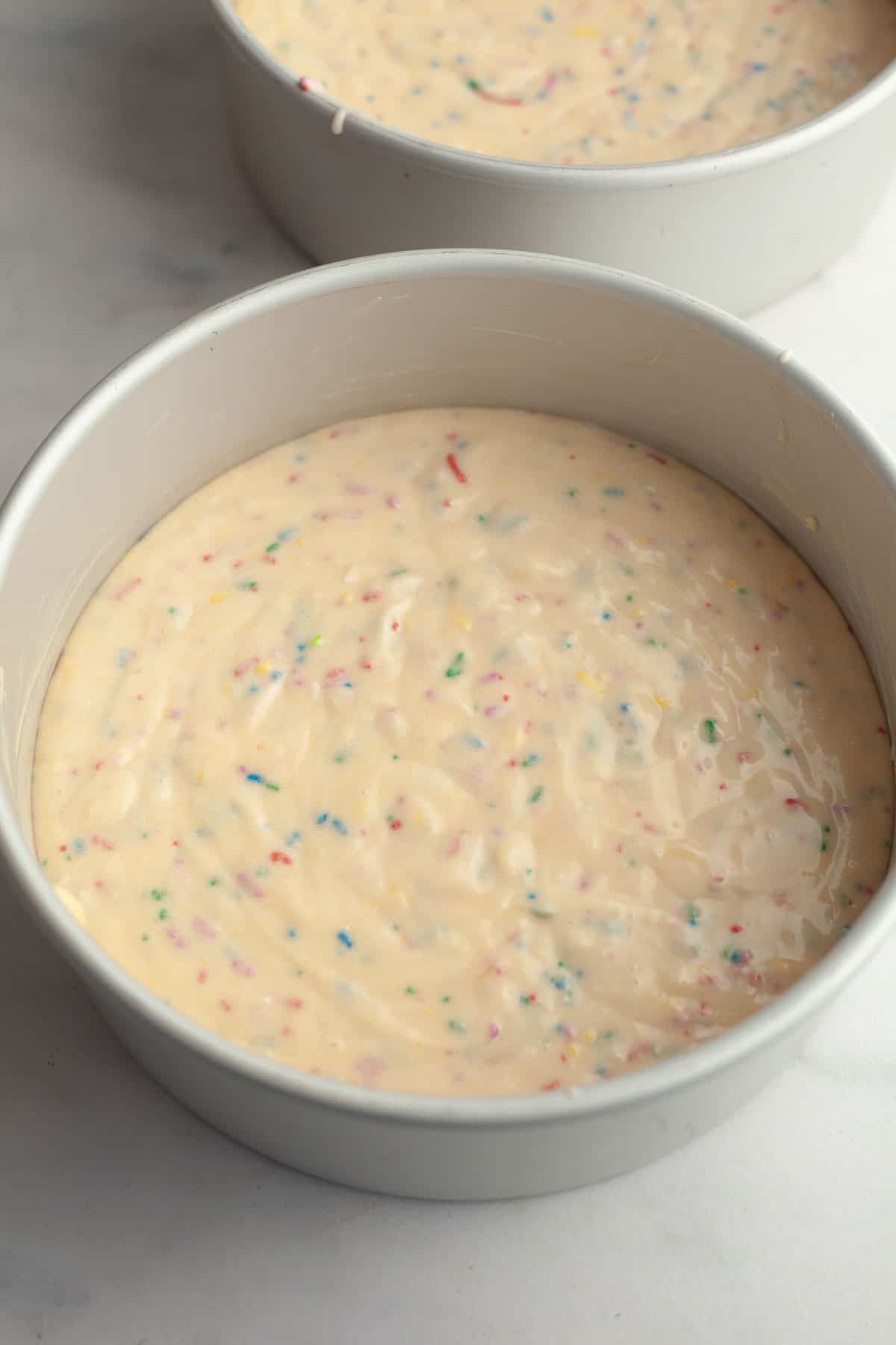 Unbaked funfetti cake in two round cake pans.