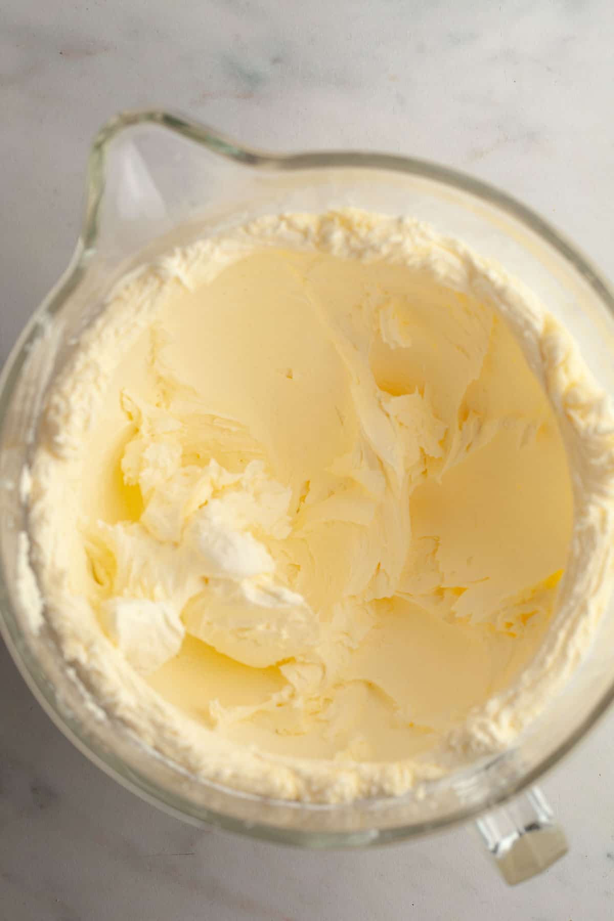 A large glass bowl with white frosting in it.