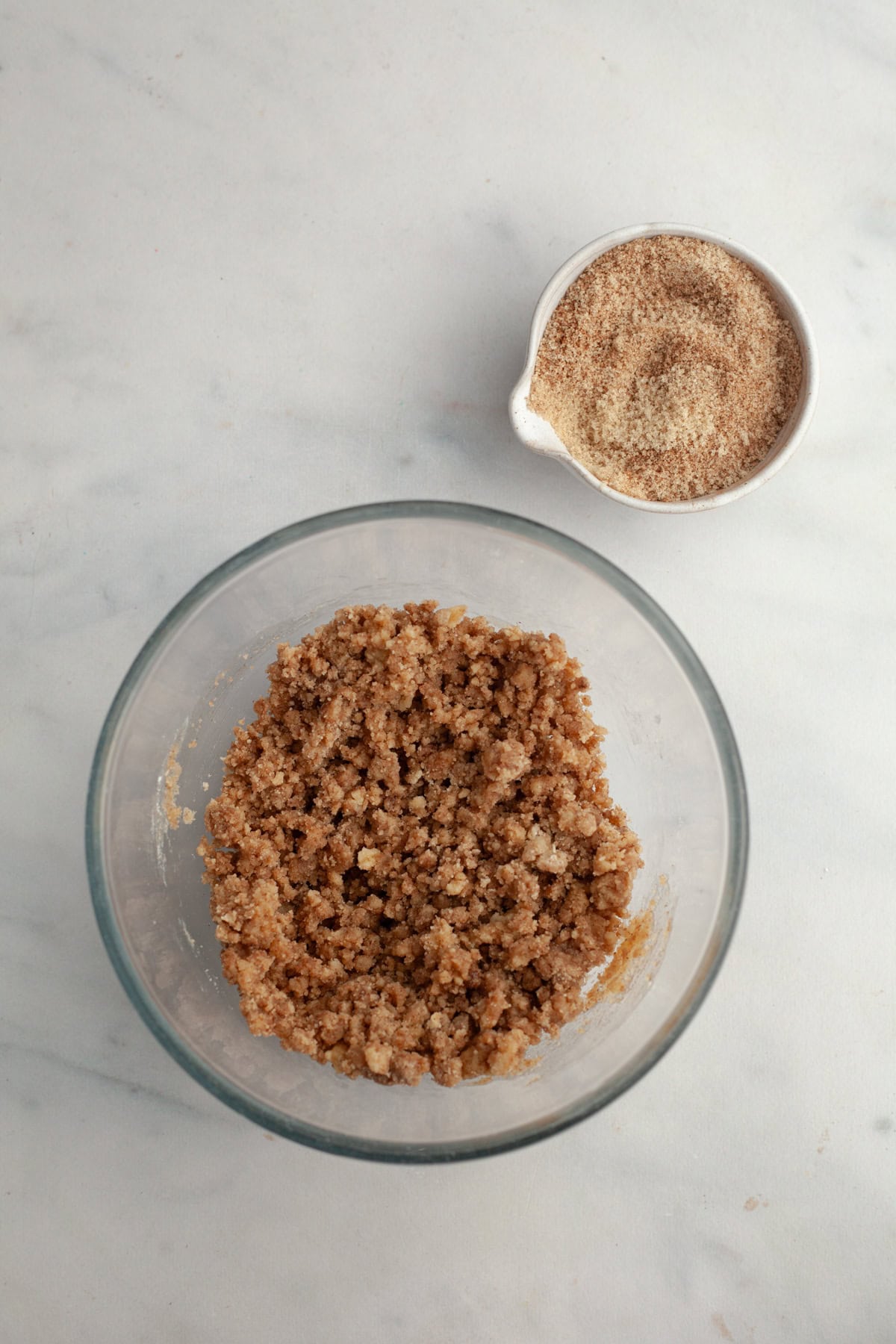 Streusel in a glass bowl and a small bowl with cinnamon sugar.