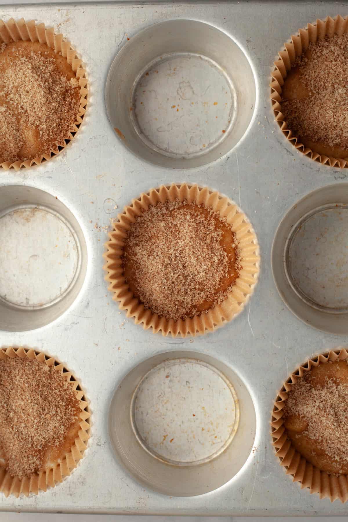 A muffin pan with unbaked banana muffins covered in cinnamon sugar.