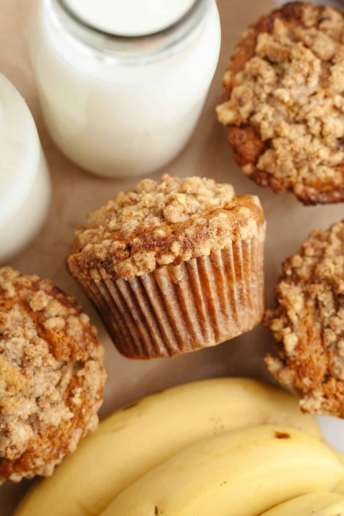 Banana coffee cake muffins with streusel topping on parchment paper.