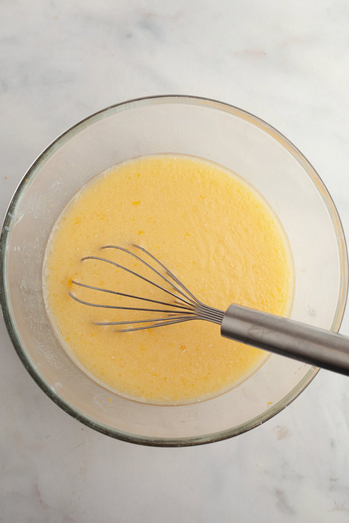 Yellow muffin batter in a glass bowl.
