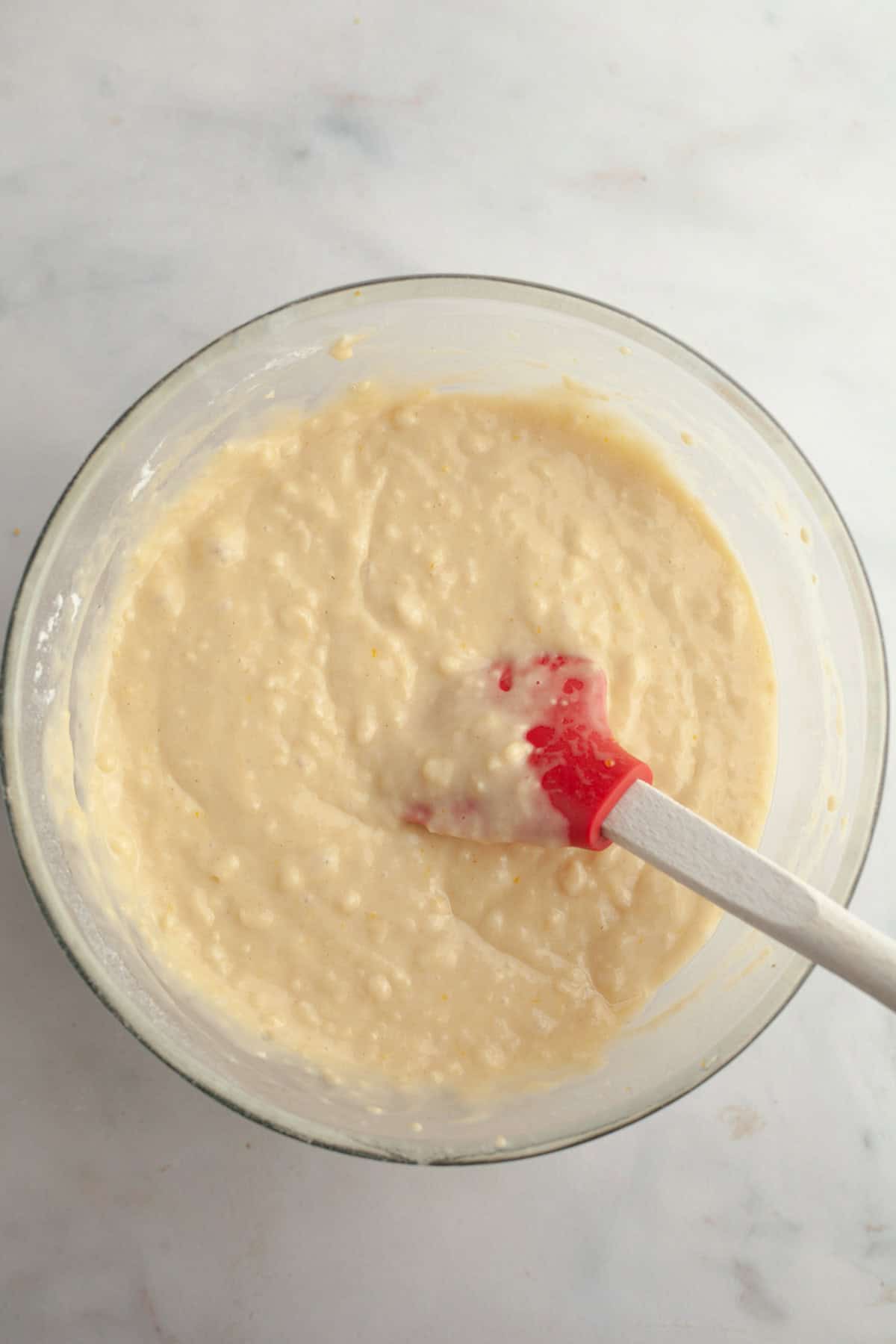 Yellow muffin batter in a glass bowl.