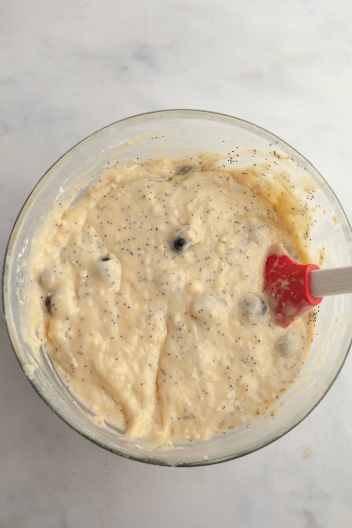 Lemon blueberry poppy seed muffin batter in a glass bowl.