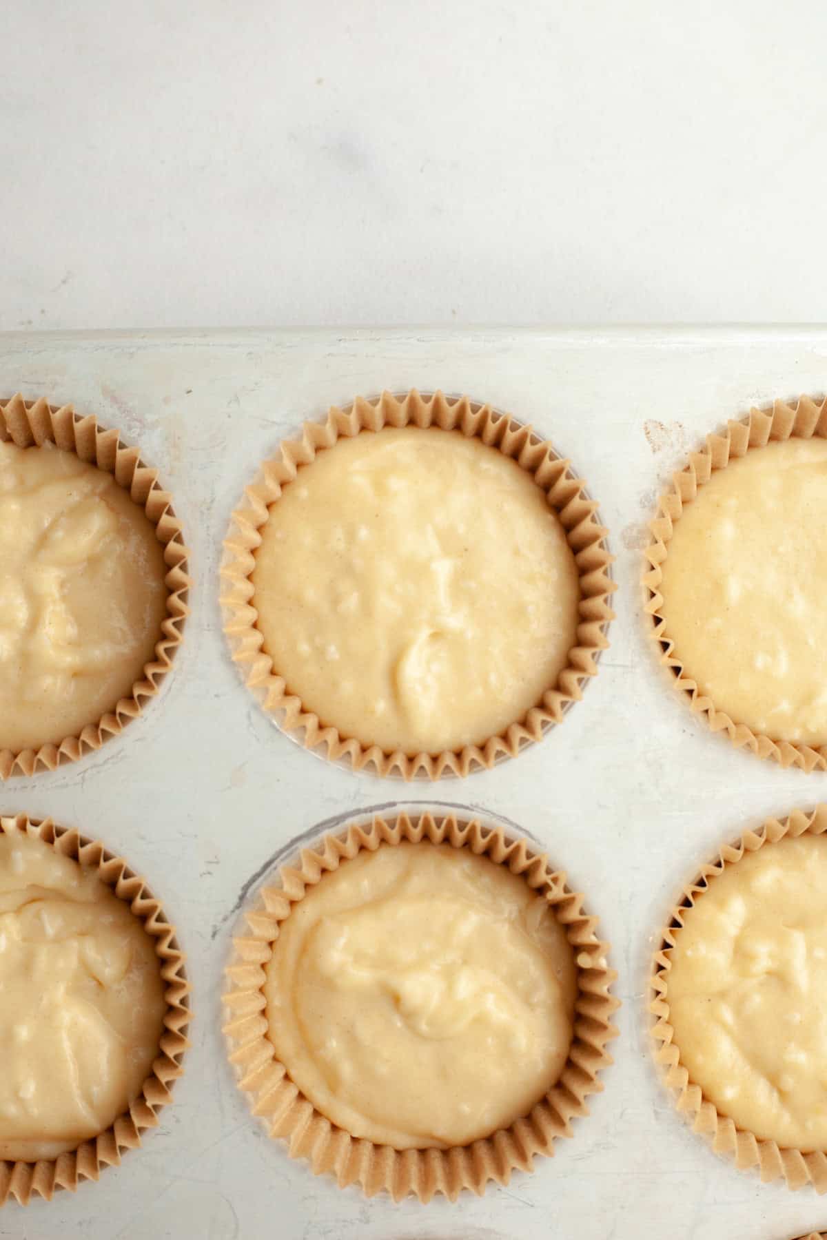 Unbaked coconut cupcakes in a cupcake pan.