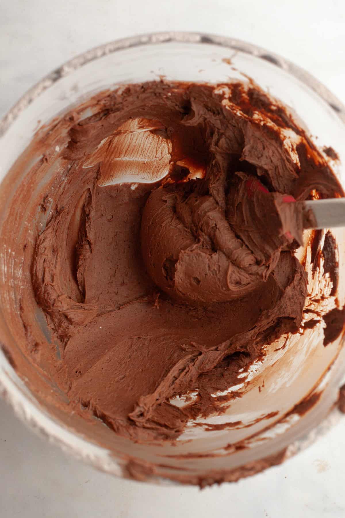 Chocolate frosting in a glass mixing bowl.