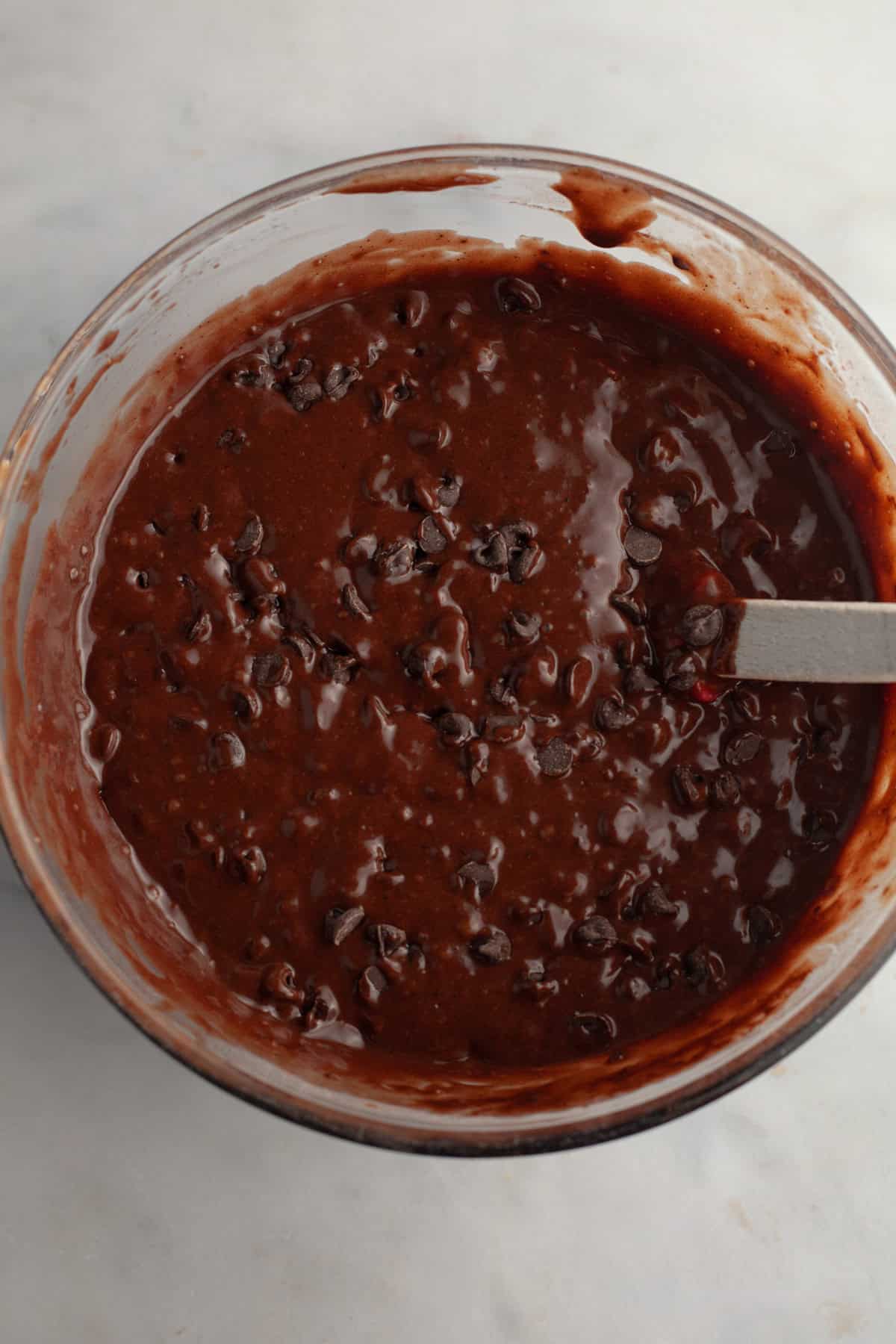 Chocolate espresso muffin batter with chocolate chips in a glass bowl.