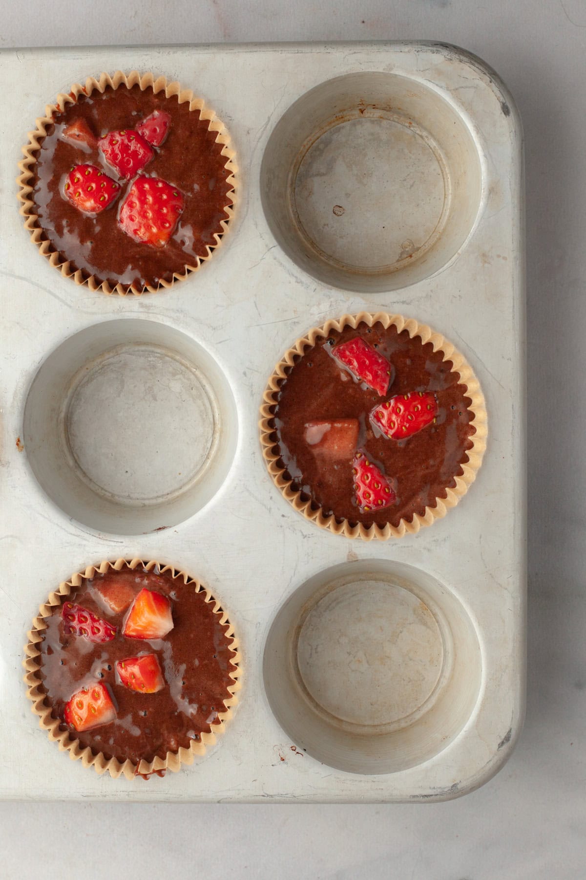 Unbaked chocolate strawberry muffins in a muffin pan.
