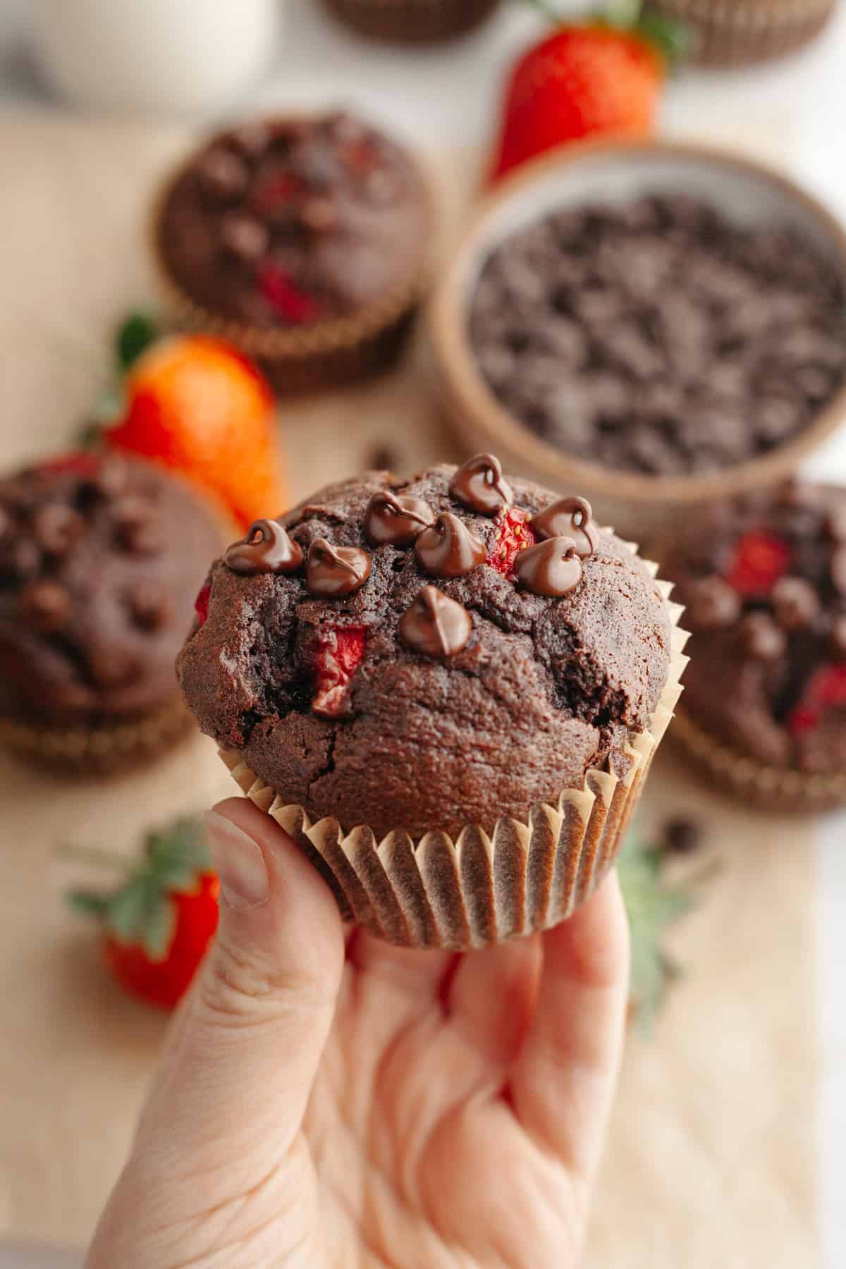 A hand holding a strawberry chocolate muffin.