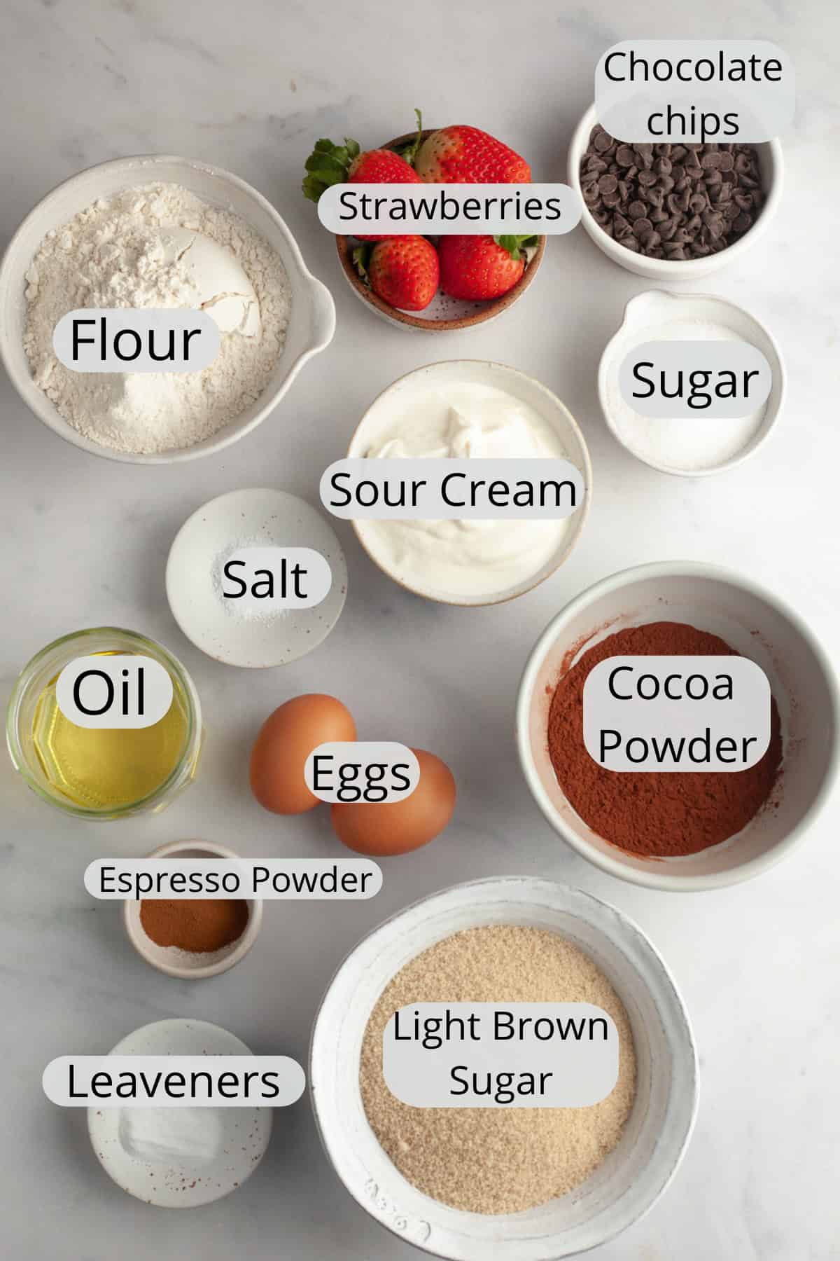 All the ingredients needed to make strawberry chocolate muffins, weighed out into small bowls.