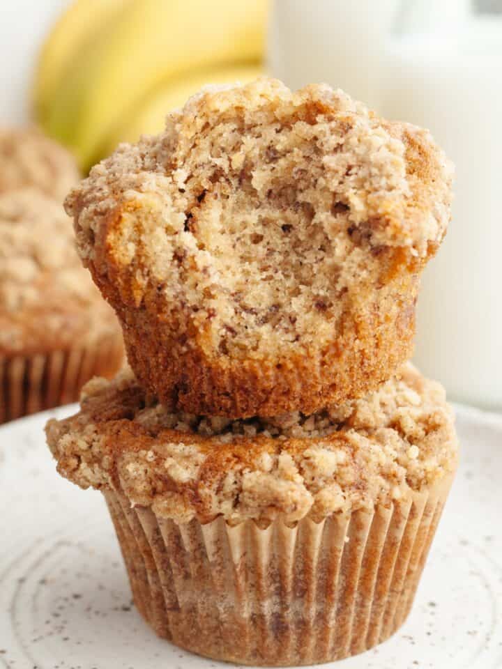 A stack of two banana coffee cake muffins, one has a bite taken out of it.