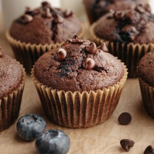 A blueberry chocolate muffin on parchment paper.