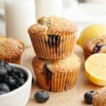 A stack of two lemon blueberry poppy seed muffins on parchment paper.