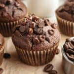 A close up of a double chocolate espresso muffin on brown parchment paper.