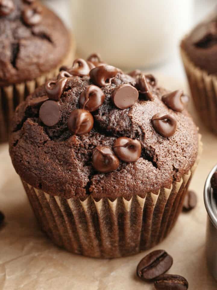 A close up of a double chocolate espresso muffin on brown parchment paper.