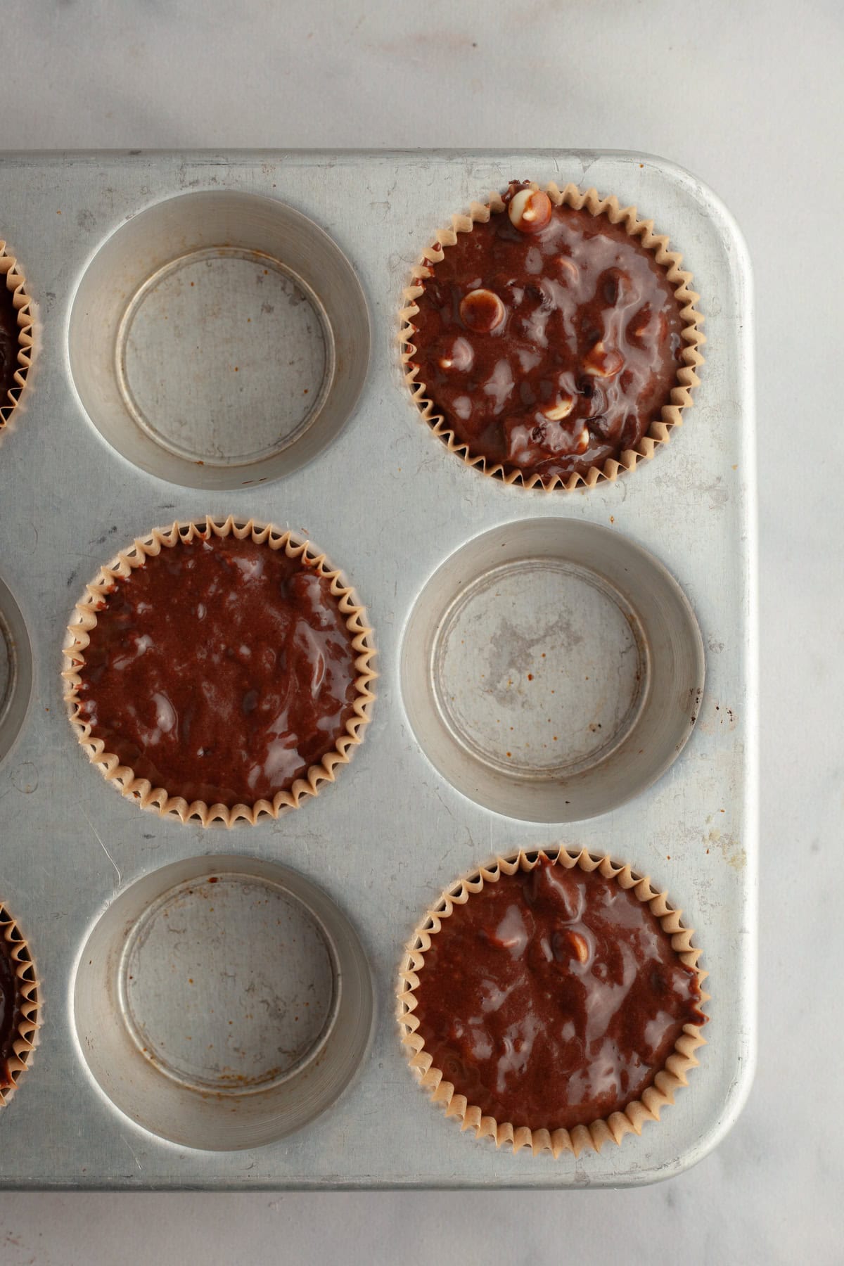 Unbaked triple chocolate muffins in a muffin pan.