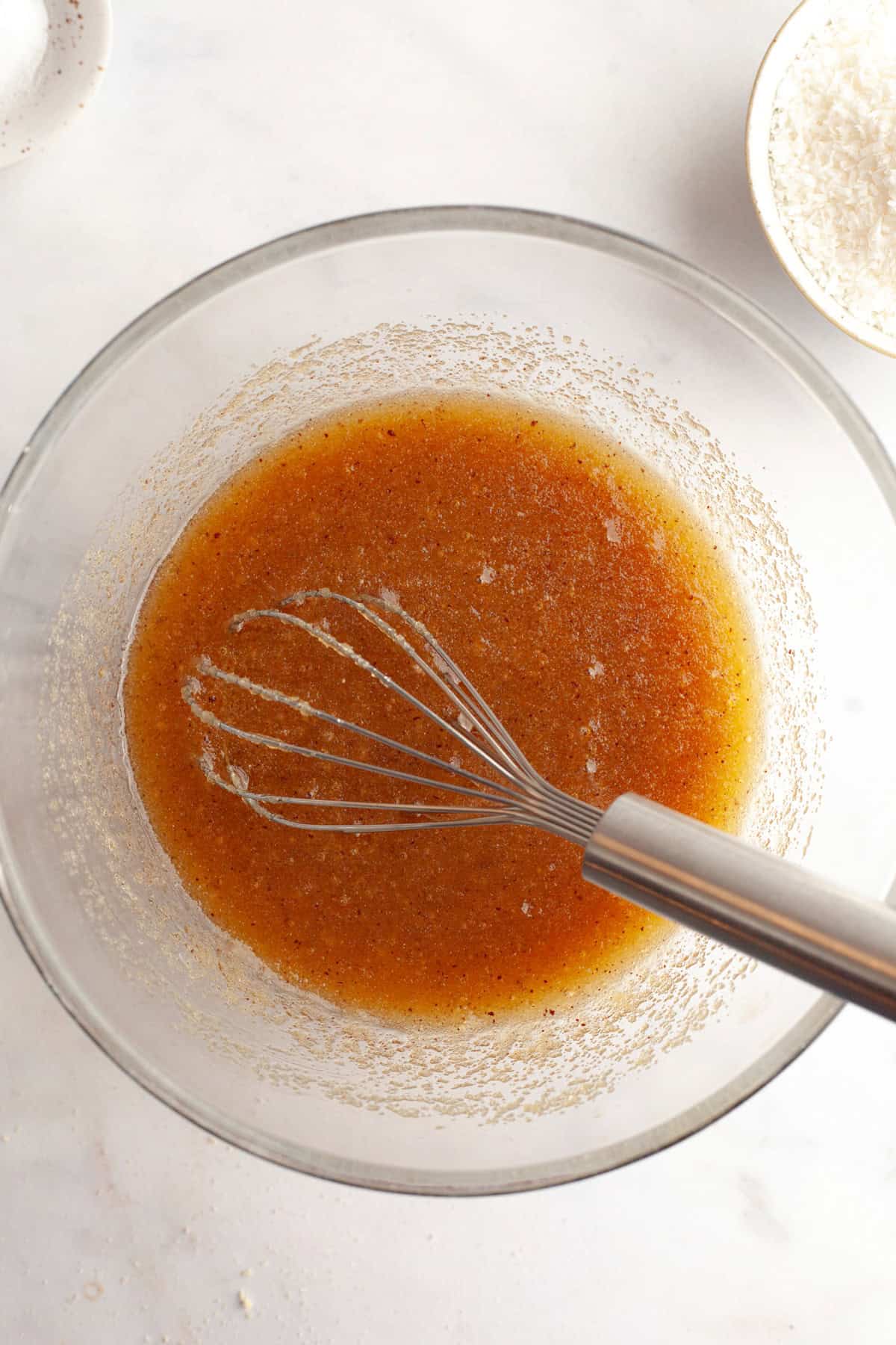Brown butter and sugar mixed together in a glass bowl with a whisk.