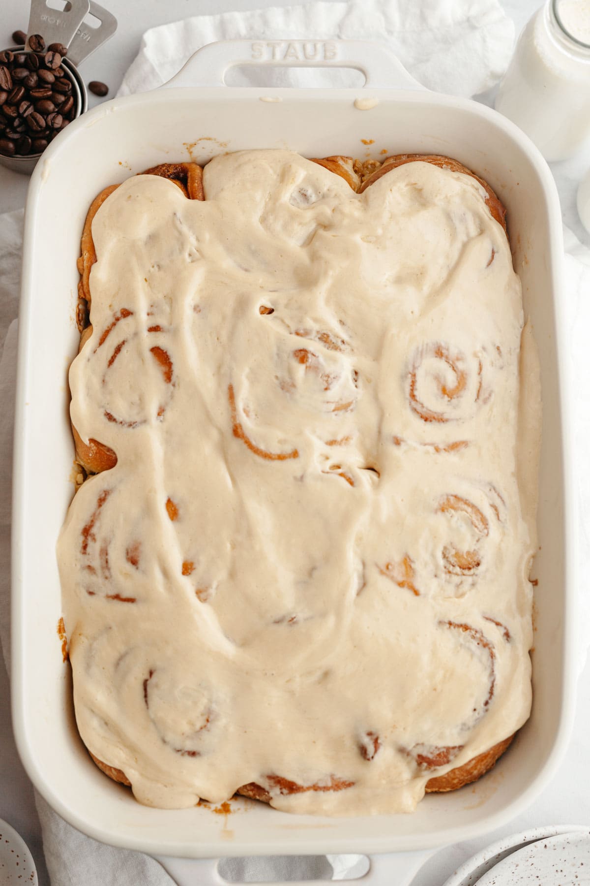 Cinnamon coffee rolls covered in maple espresso icing in a rectangular dish.