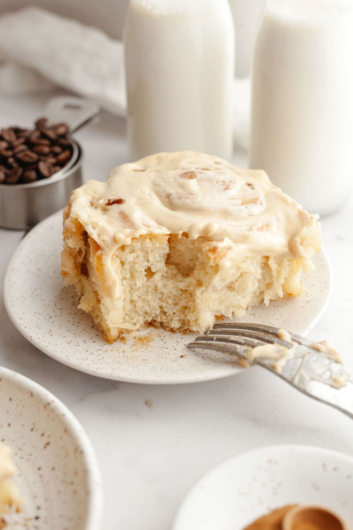A cinnamon coffee roll with maple espresso icing on a plate.