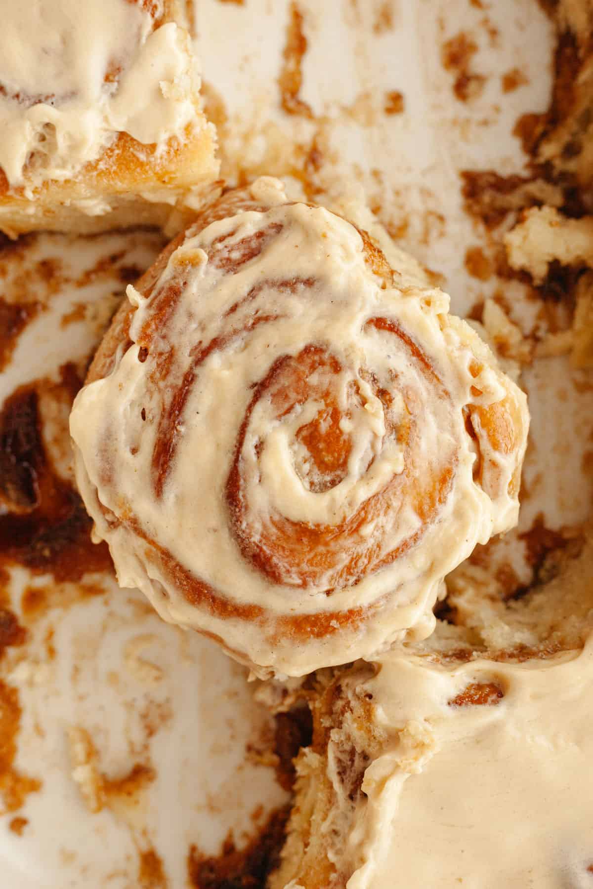 A cinnamon coffee roll with maple espresso icing in a dish.