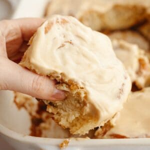 A hand grabbing a cinnamon coffee roll.
