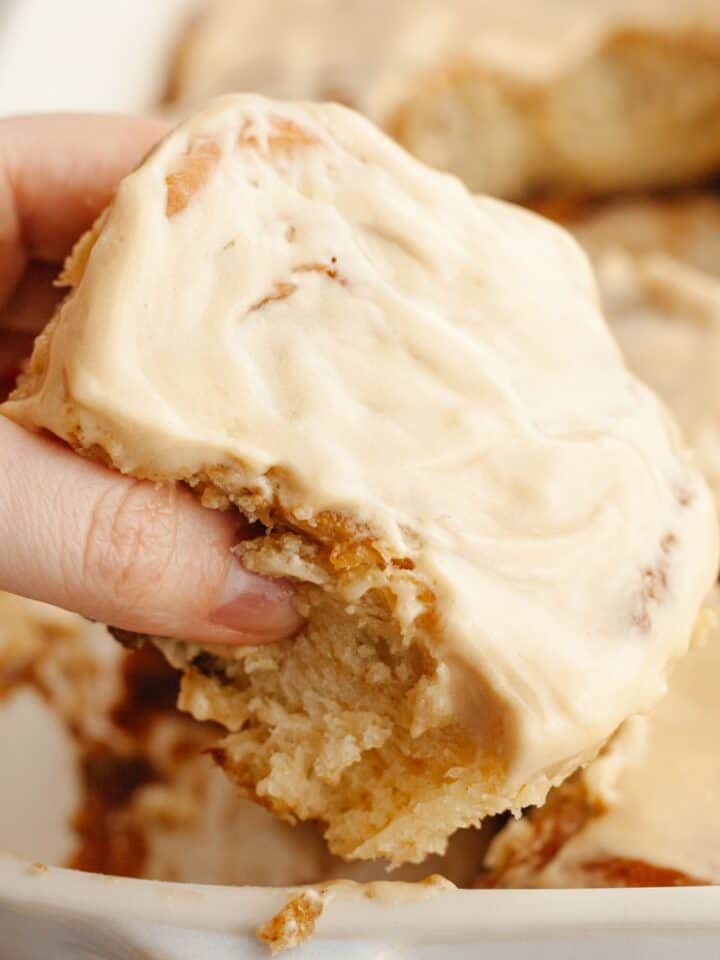 A hand grabbing a cinnamon coffee roll.