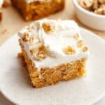 A slice of mini carrot cake with cream cheese frosting and chopped walnuts.
