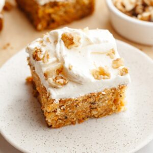 A slice of mini carrot cake with cream cheese frosting and chopped walnuts.