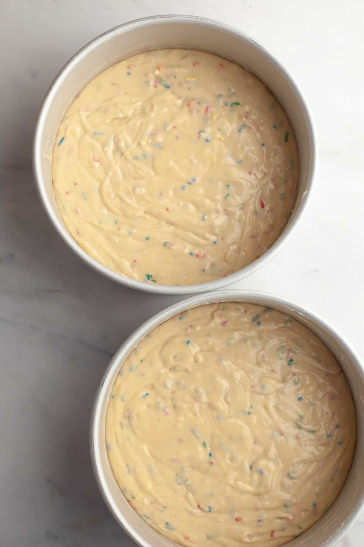 Funfetti cake batter in two cake pans, unbaked.