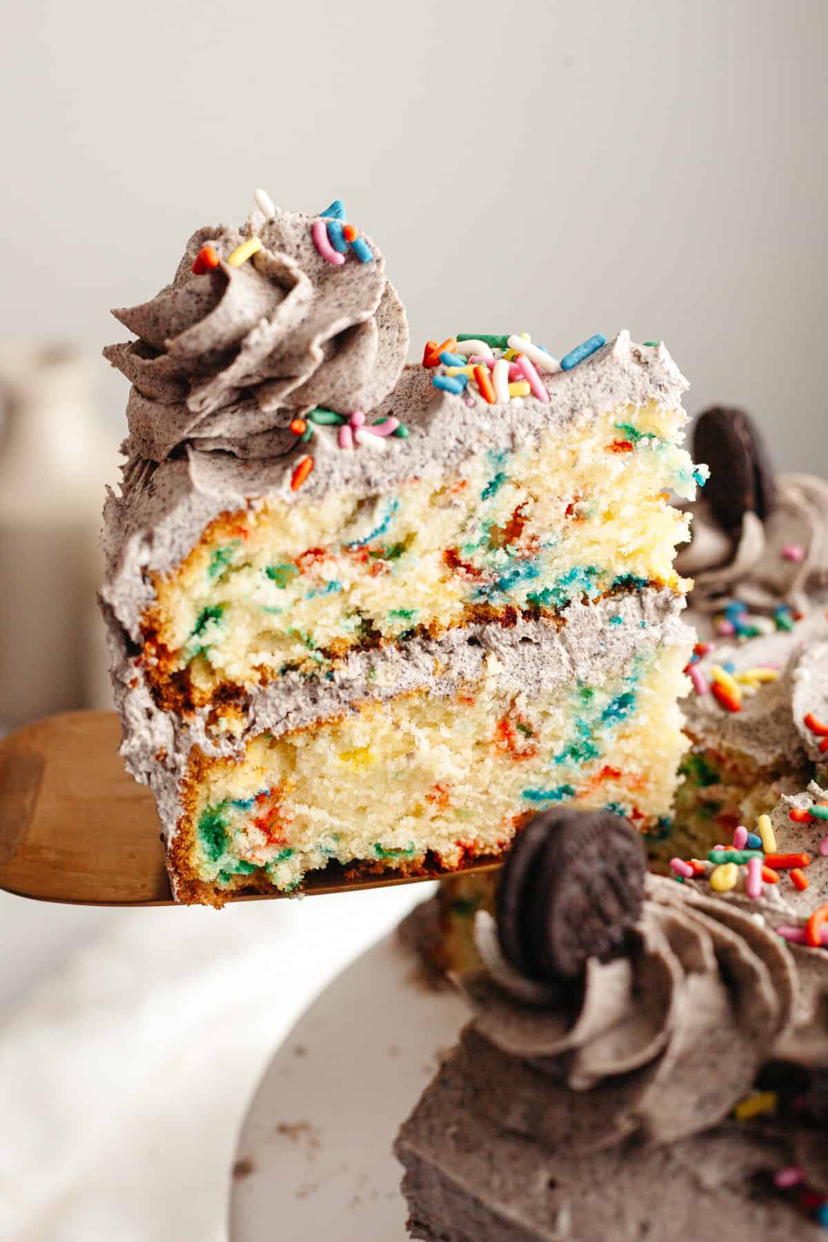 A slice of Oreo funfetti cake being lifted out with a cake server.
