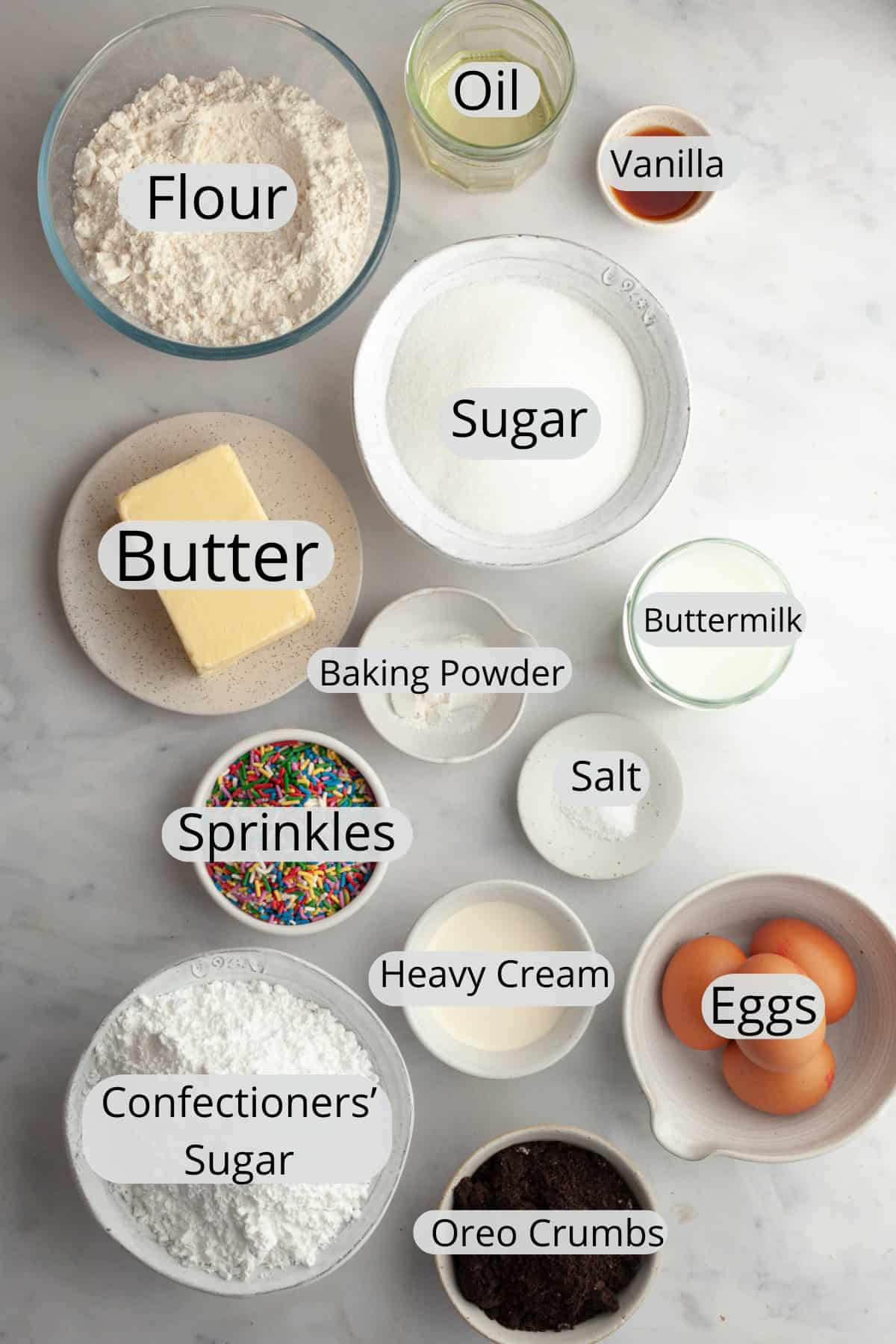 All the ingredients needed to make a funfetti Oreo cake, weighed out into small bowls.