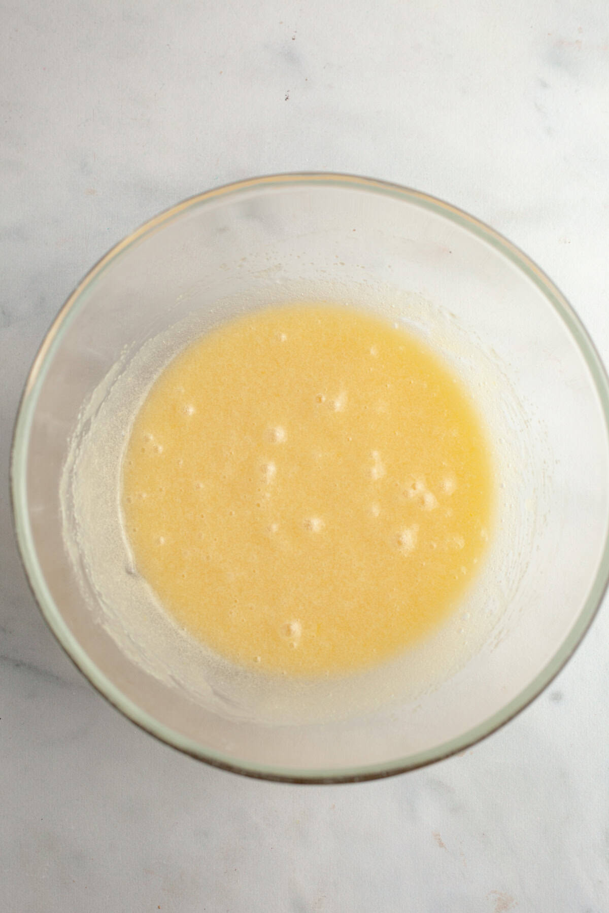 A glass bowl with a beige liquid in it.