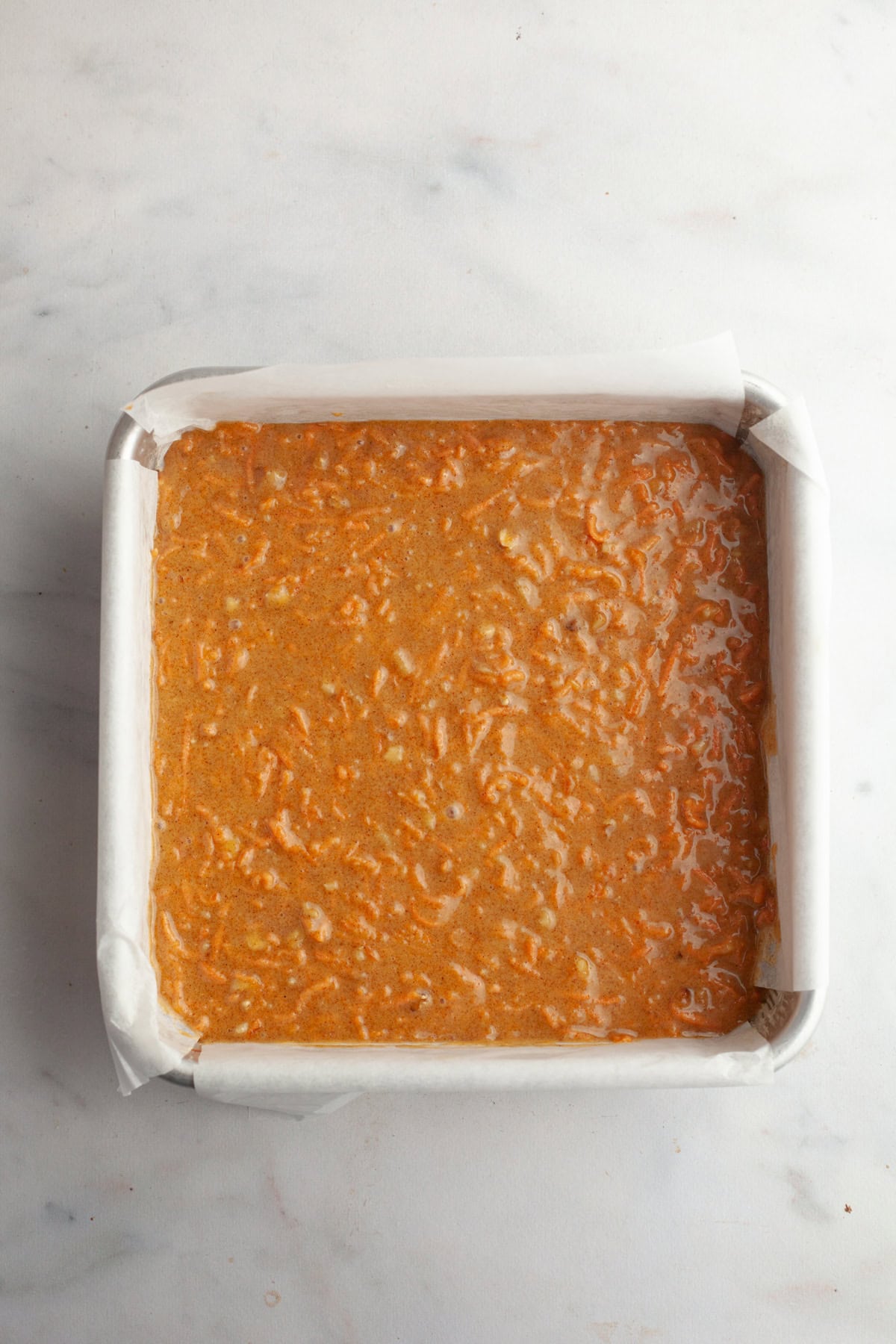Unbaked carrot cake in a square pan.