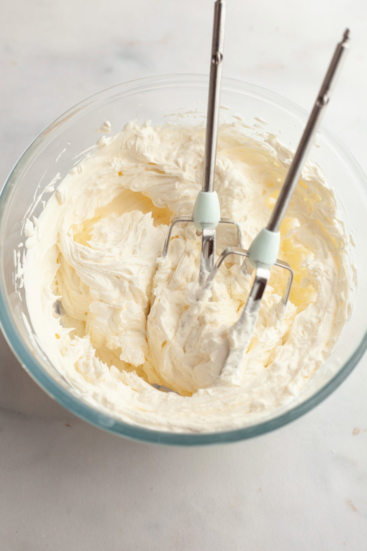 Cream cheese frosting in a glass bowl.