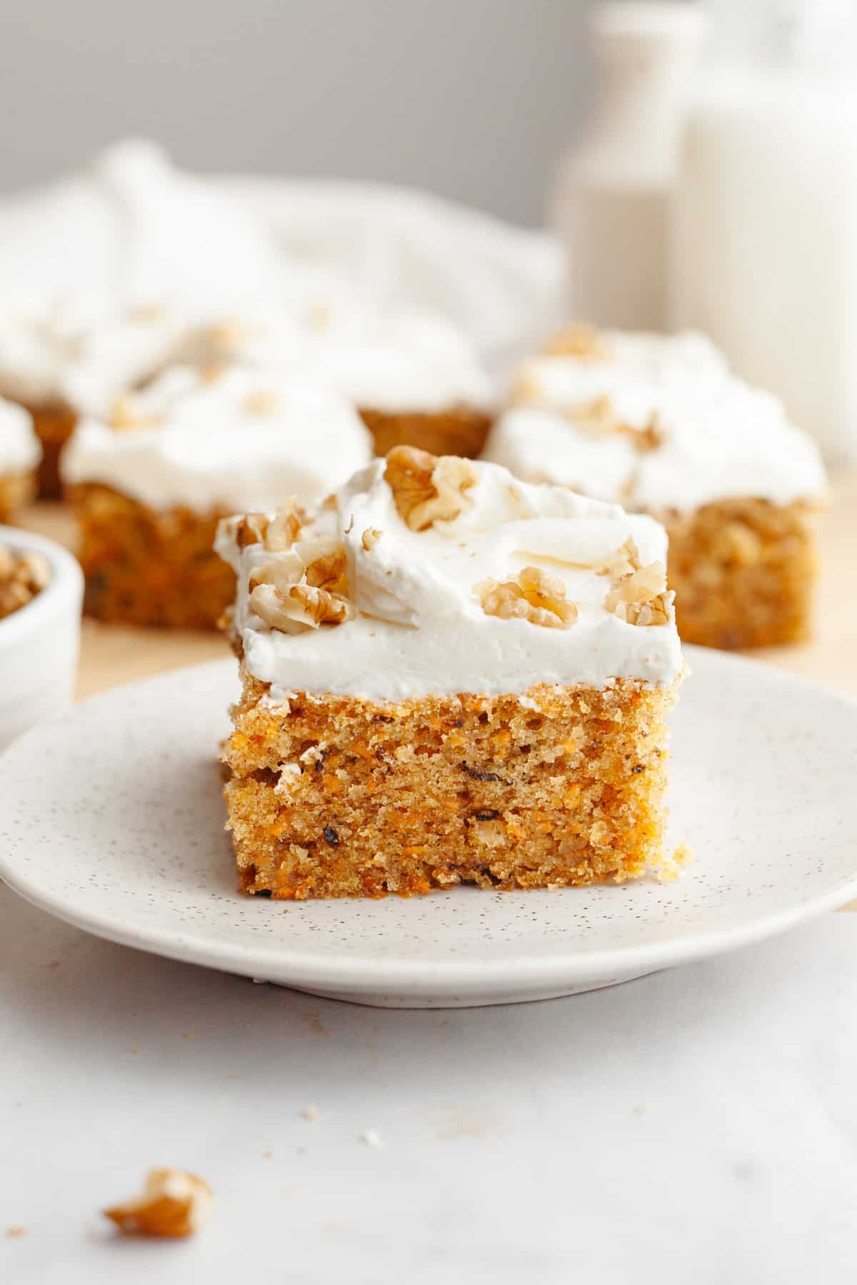 A slice of mini carrot cake with cream cheese frosting on a small plate.