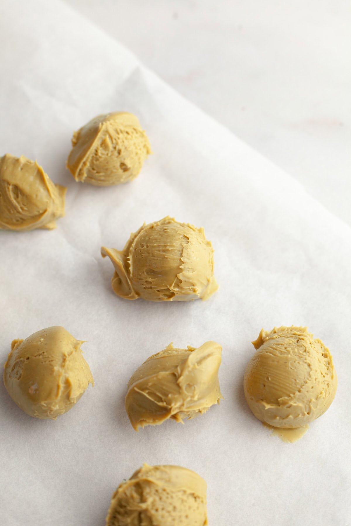 Scooped out balls of pistachio cream on parchment paper.