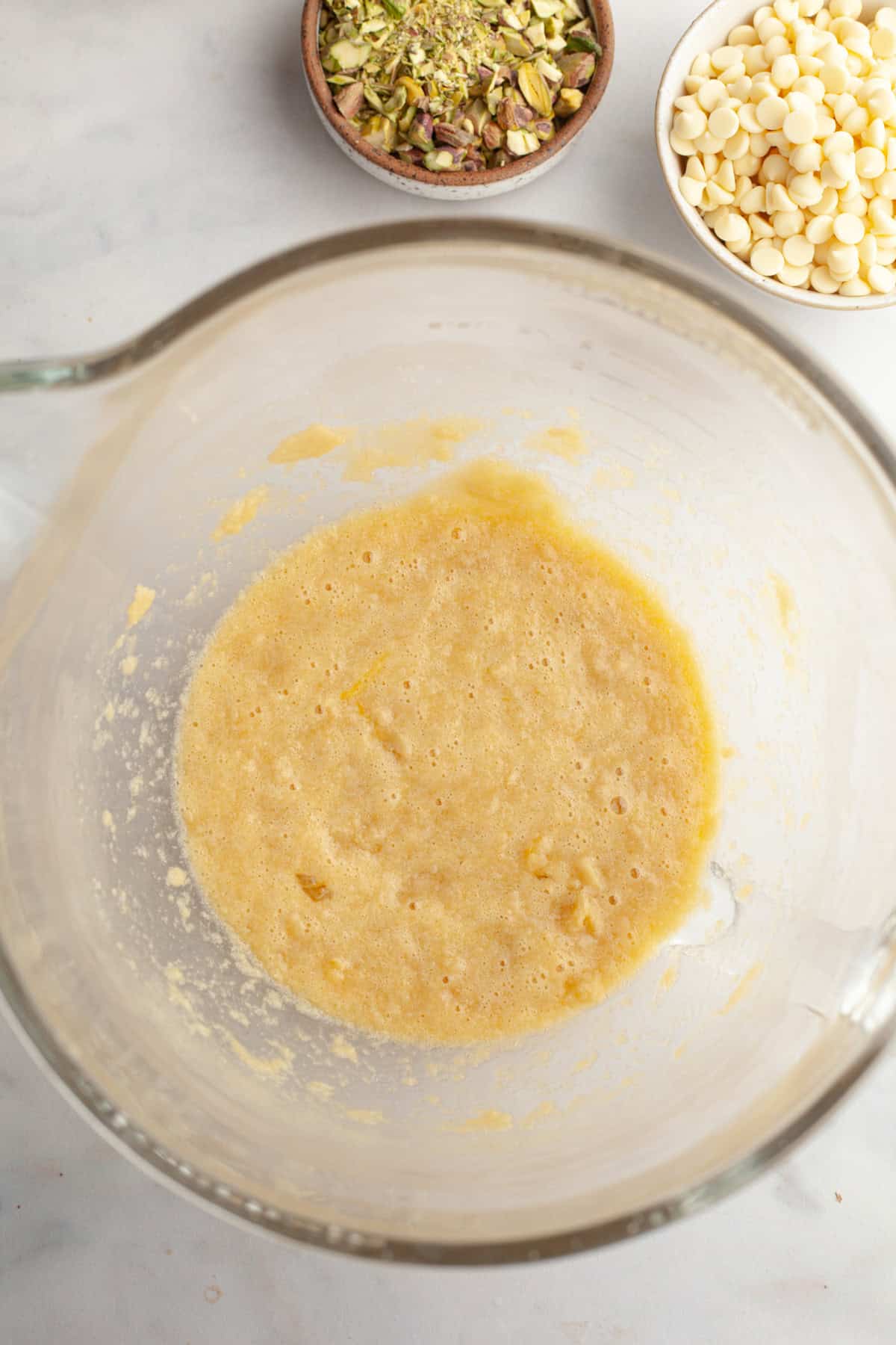A glass mixing bowl with a yellow batter in it.