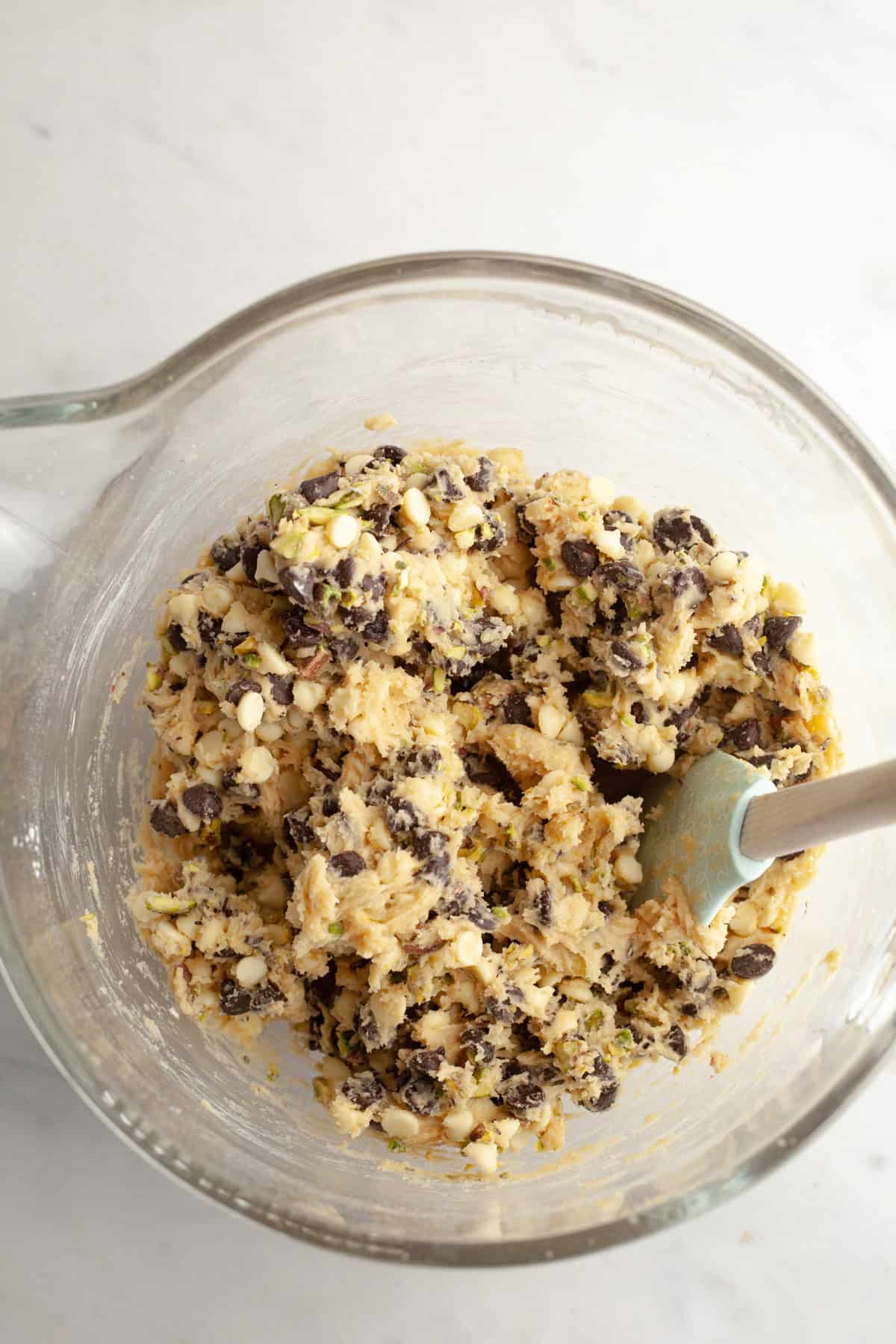A mixing bowl with pistachio chocolate chip cookie dough in it.