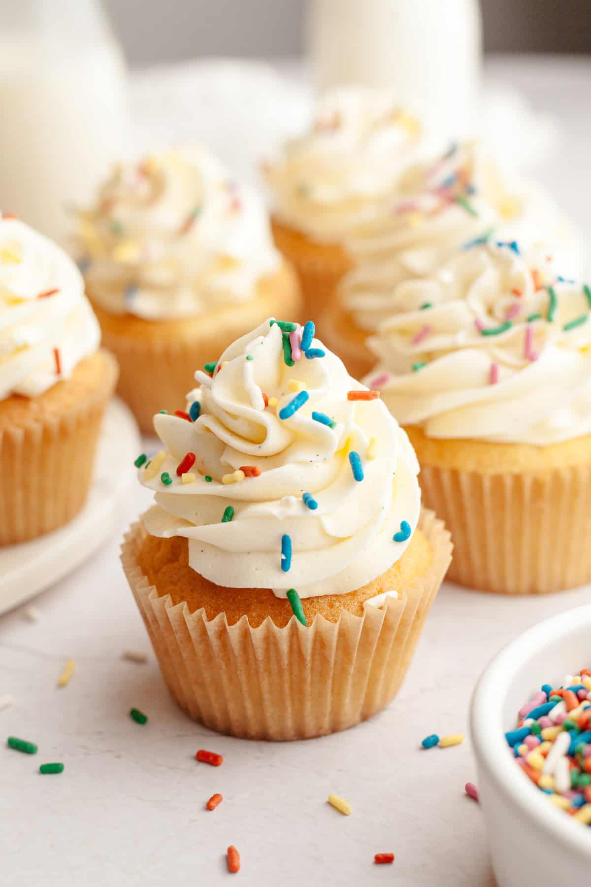 A close up of vanilla bean cupcakes with rainbow sprinkles.