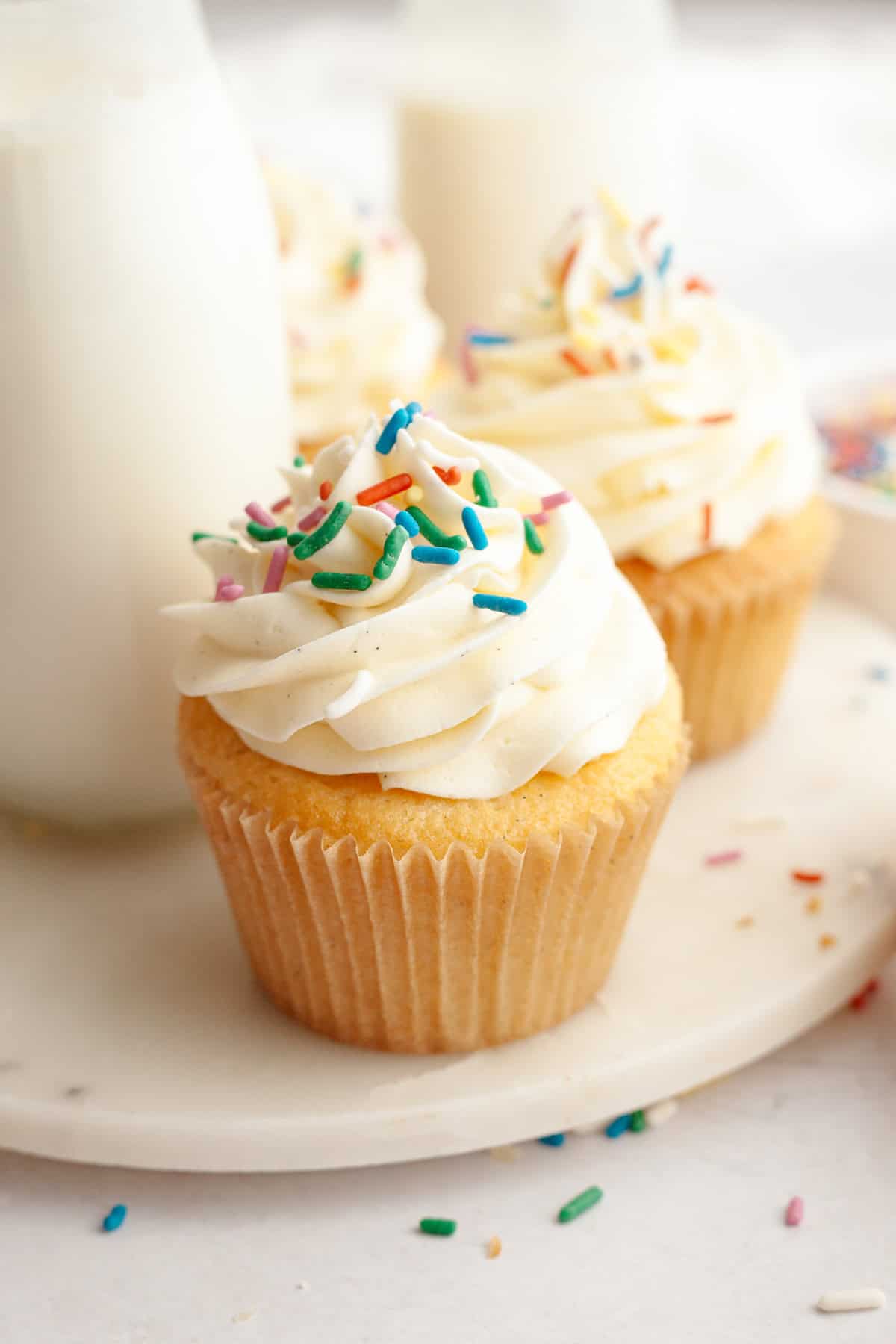 A close up of a vanilla bean cupcake with rainbow sprinkles.